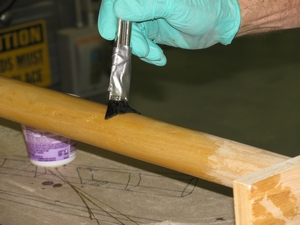 Apply a seal coat of G/Flex epoxy to a wooden paddle.