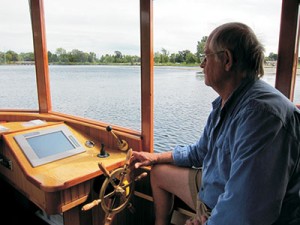 Moores at the helm of Sparks, his Hybrid Electric Launch. The classic-looking pilothouse provides a good view of the passing landscape.