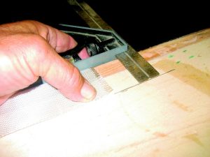 A combination square is used to mark the two edges along the entire length of the corner before applying reinforcing fiber tape.